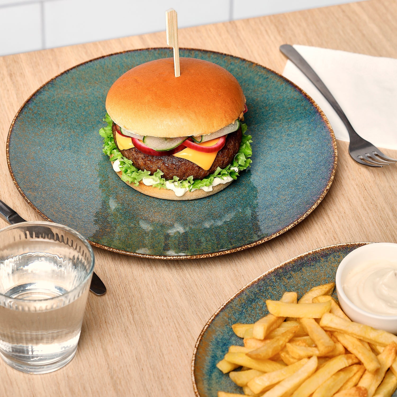 BonBistro Cirro dinerbord in gebruik met hamburger, water en bord friet met mayonaise ernaast
