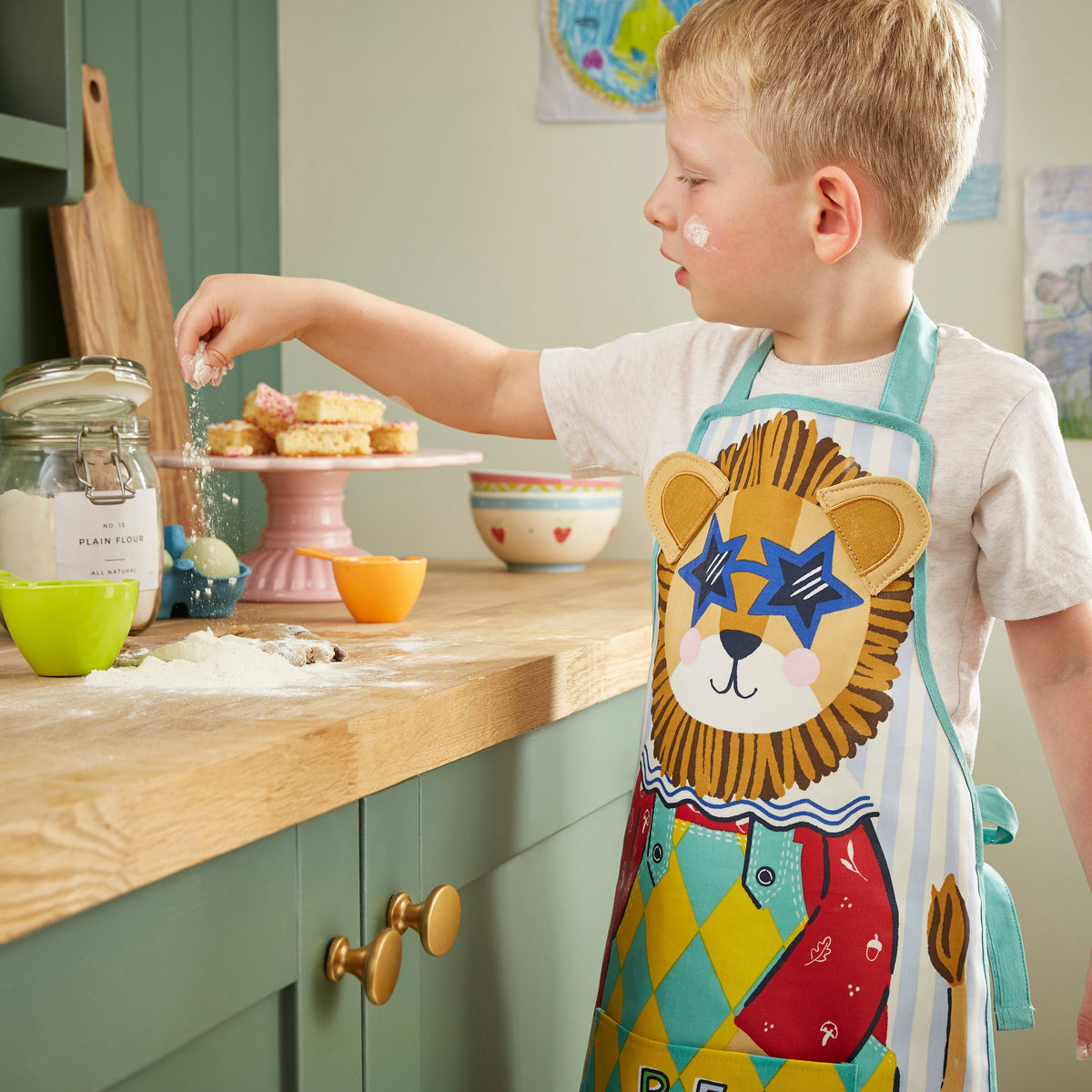 Ulster Weavers Kinderschort - Leon Lion, kinderen dragen samen de kinderschorten in de keuken