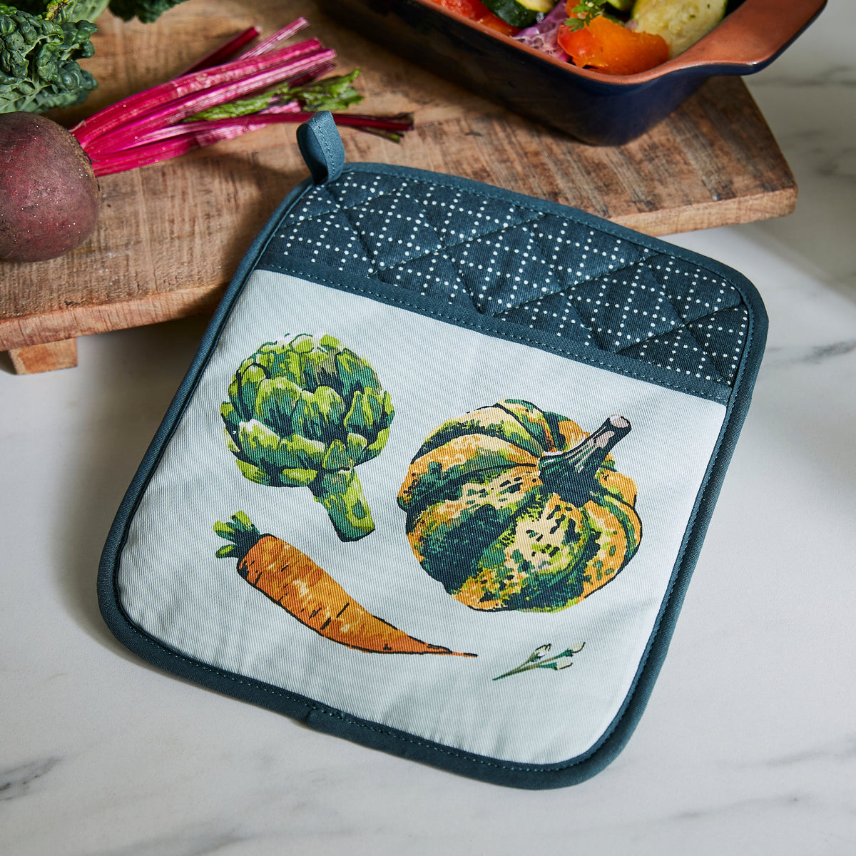 Ulster Weavers Pannenlap - Vegetable Medley, pannenlap op een snijplank met groenten