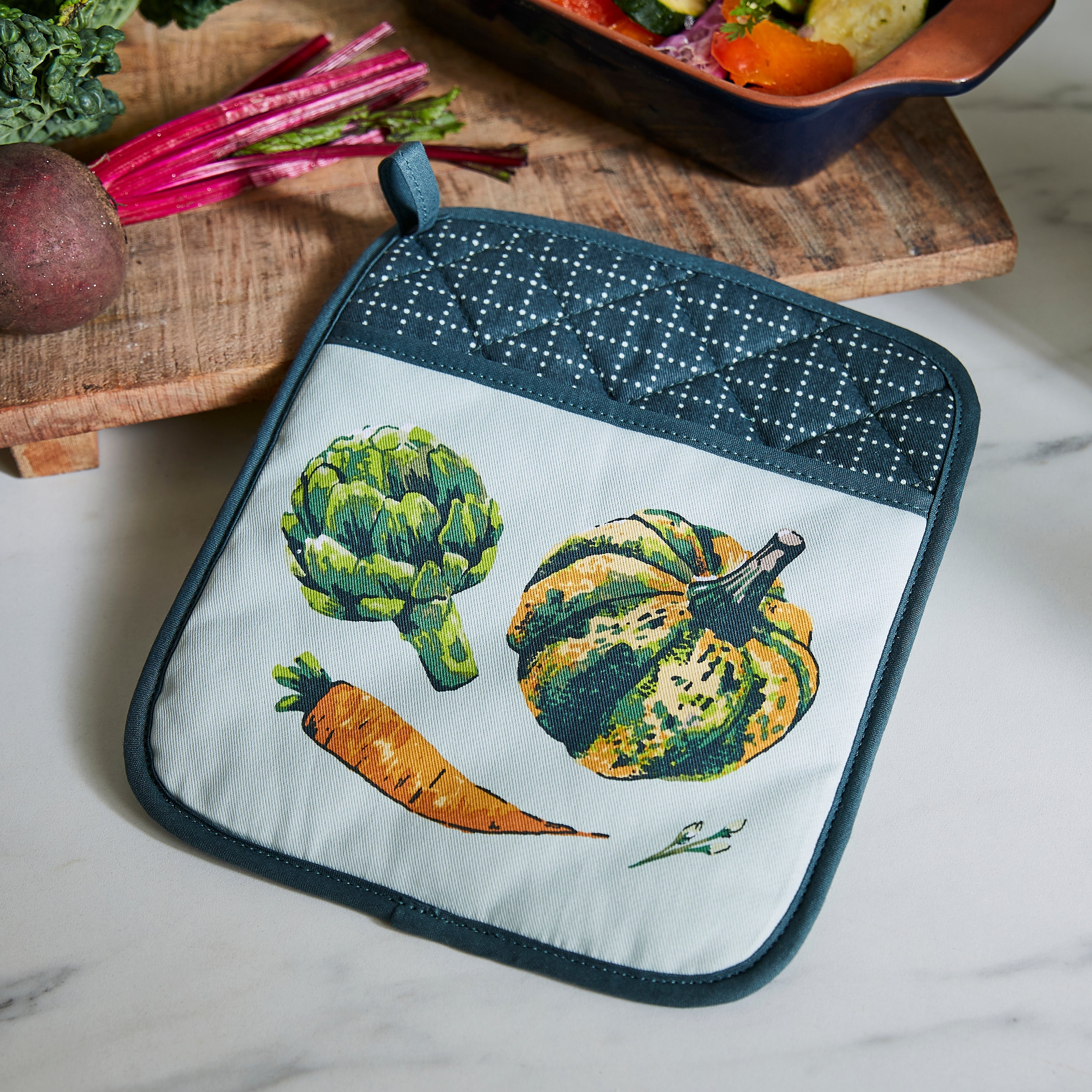 Ulster Weavers Pannenlap - Vegetable Medley, pannenlap op een snijplank met groenten