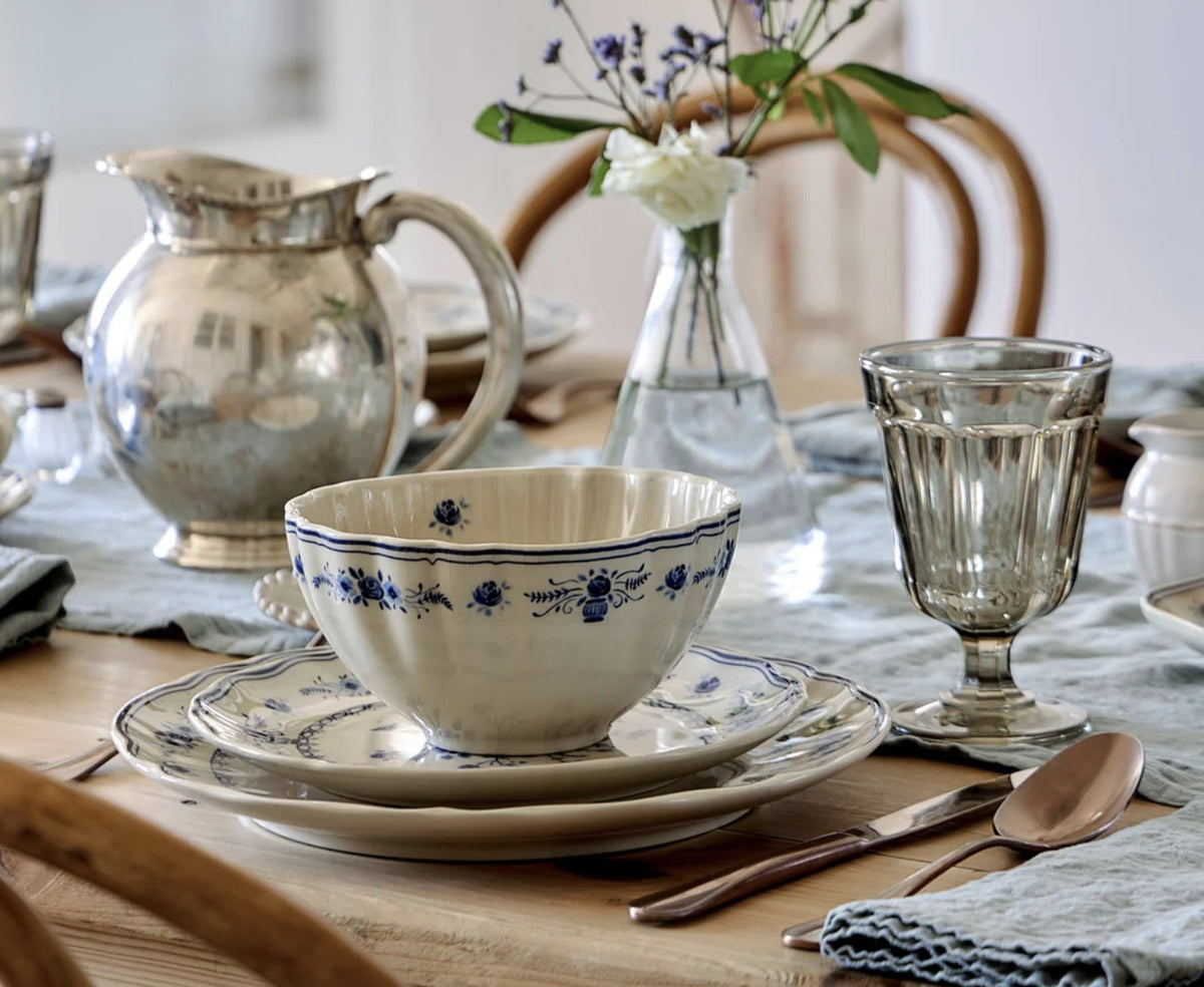 Costa Nova Vila Kom Beige-Blauw op tafel met een zilveren kan en een vaasje met witte rozen en lavendel op de achtergrond