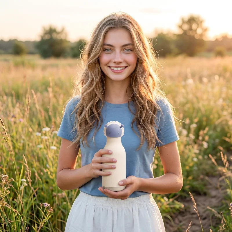 Vrouw in een veld houdt de Asobu Bestie Thermosfles Schaap vast