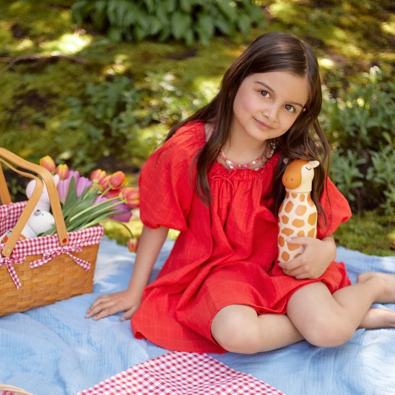 Meisje in rode jurk zit op een picknickkleed met de Asobu Bestie Thermosfles Giraffe