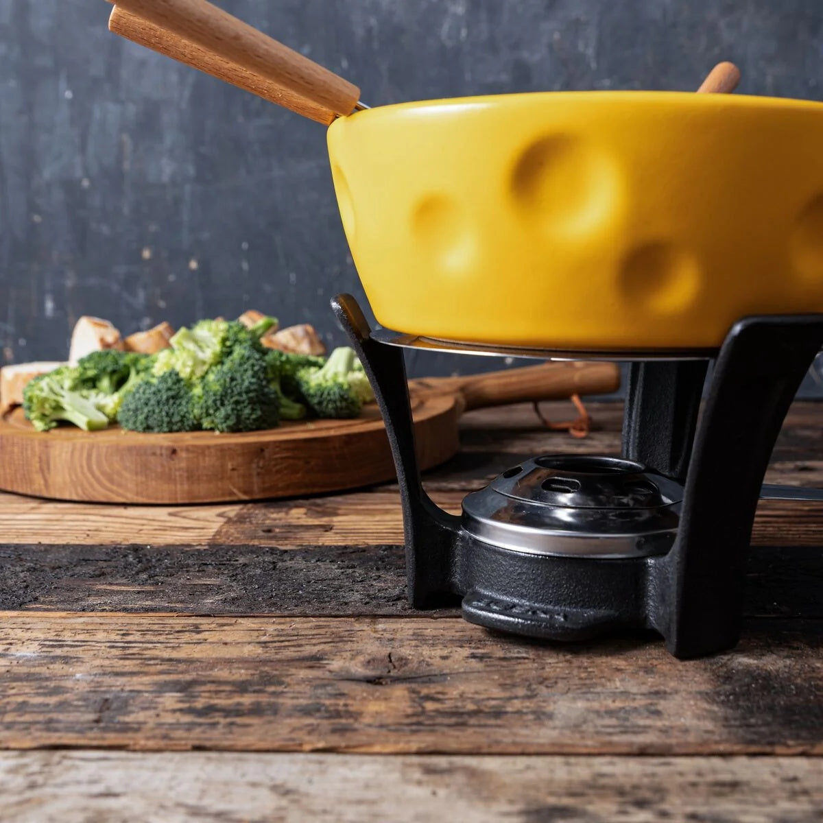 Boska Fondueset Super Cheesy op een houten tafel met een bakje broccoli ernaast