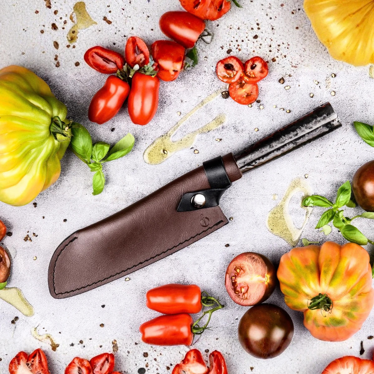 Santokumes met olijfhouten handvat en leren hoes tussen kleurrijke tomaten