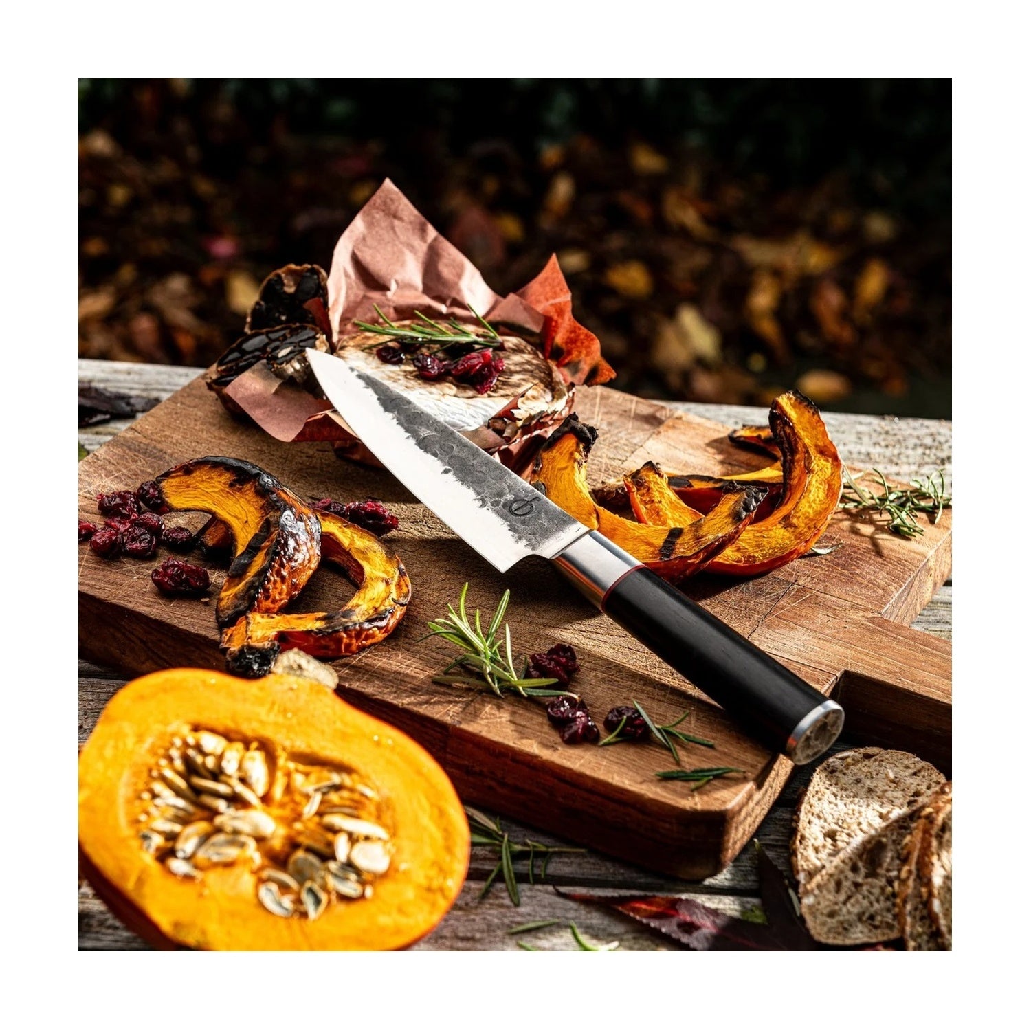 Forged Sebra koksmes te midden van herfstgerechten met gegrilde pompoen op een houten snijplank