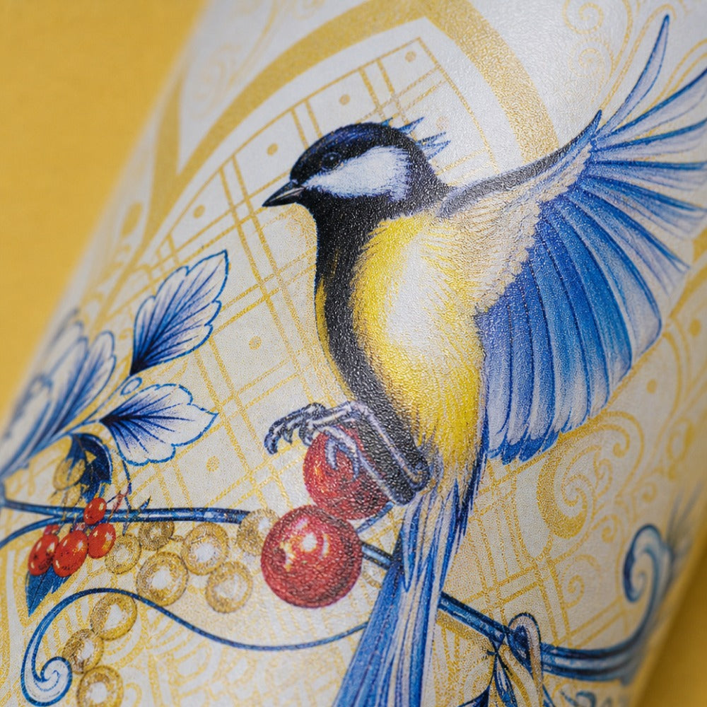 Close-up van het gele vogel- en besjesmotief op de IZY Thermosbeker Saffron Gold