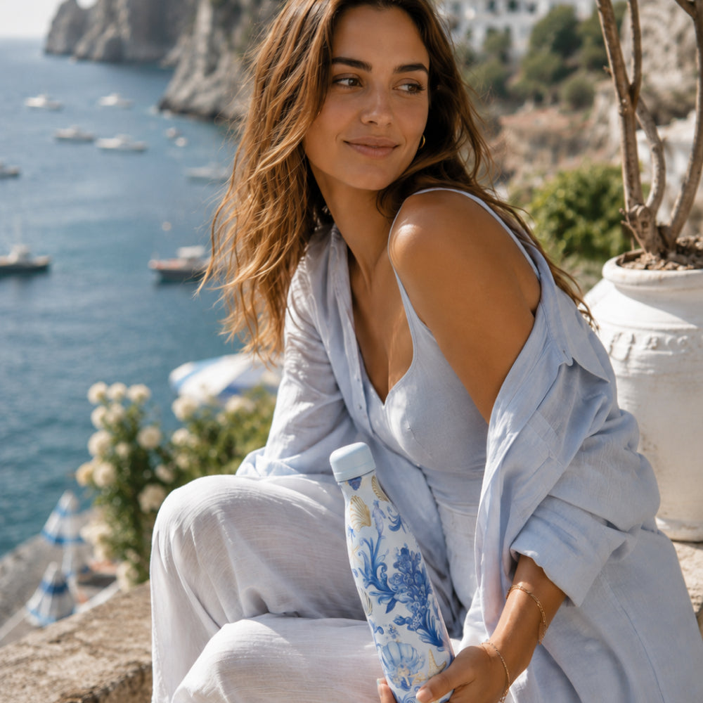 Vrouw bij het water houdt de blauwe IZY Thermosfles Blu Marina vast