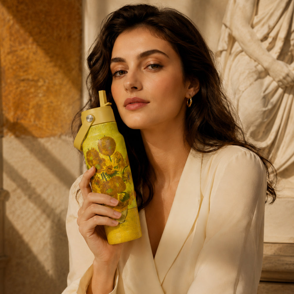 Vrouw in crèmekleurige jurk houdt de gele IZY Travel Bottle Sunflowers vast