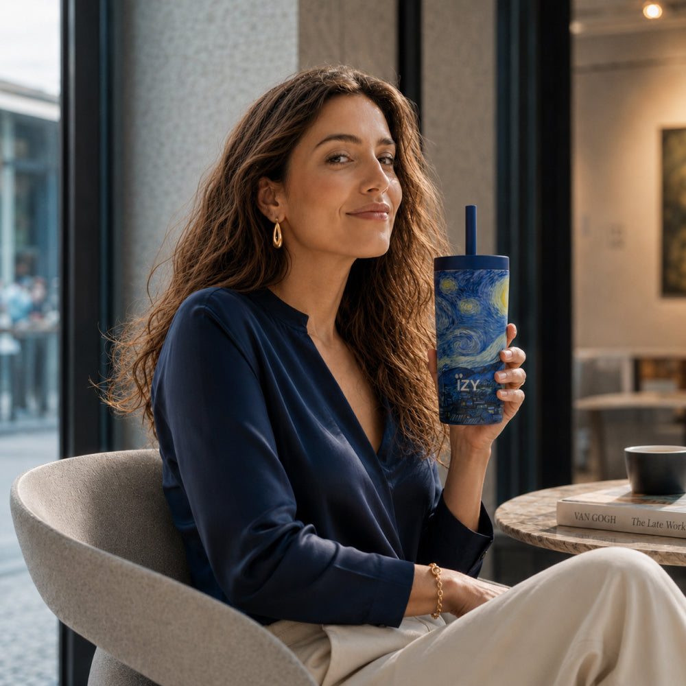 Vrouw aan een tafel houdt de donkerblauwe IZY Tumbler Starry Night met rietje vast