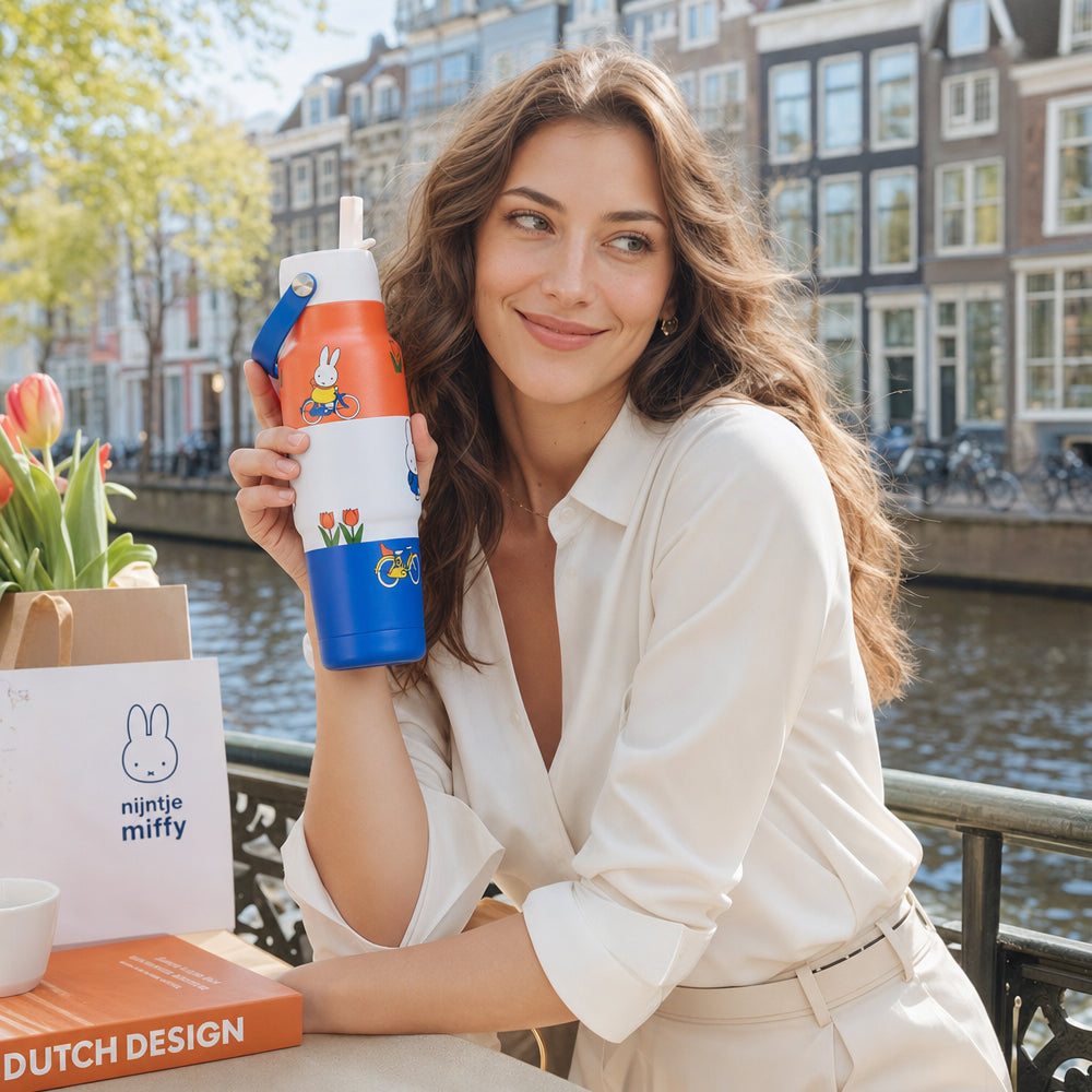 Vrouw bij een gracht met tulpen houdt de IZY Travel Bottle Flag Nijntje vast