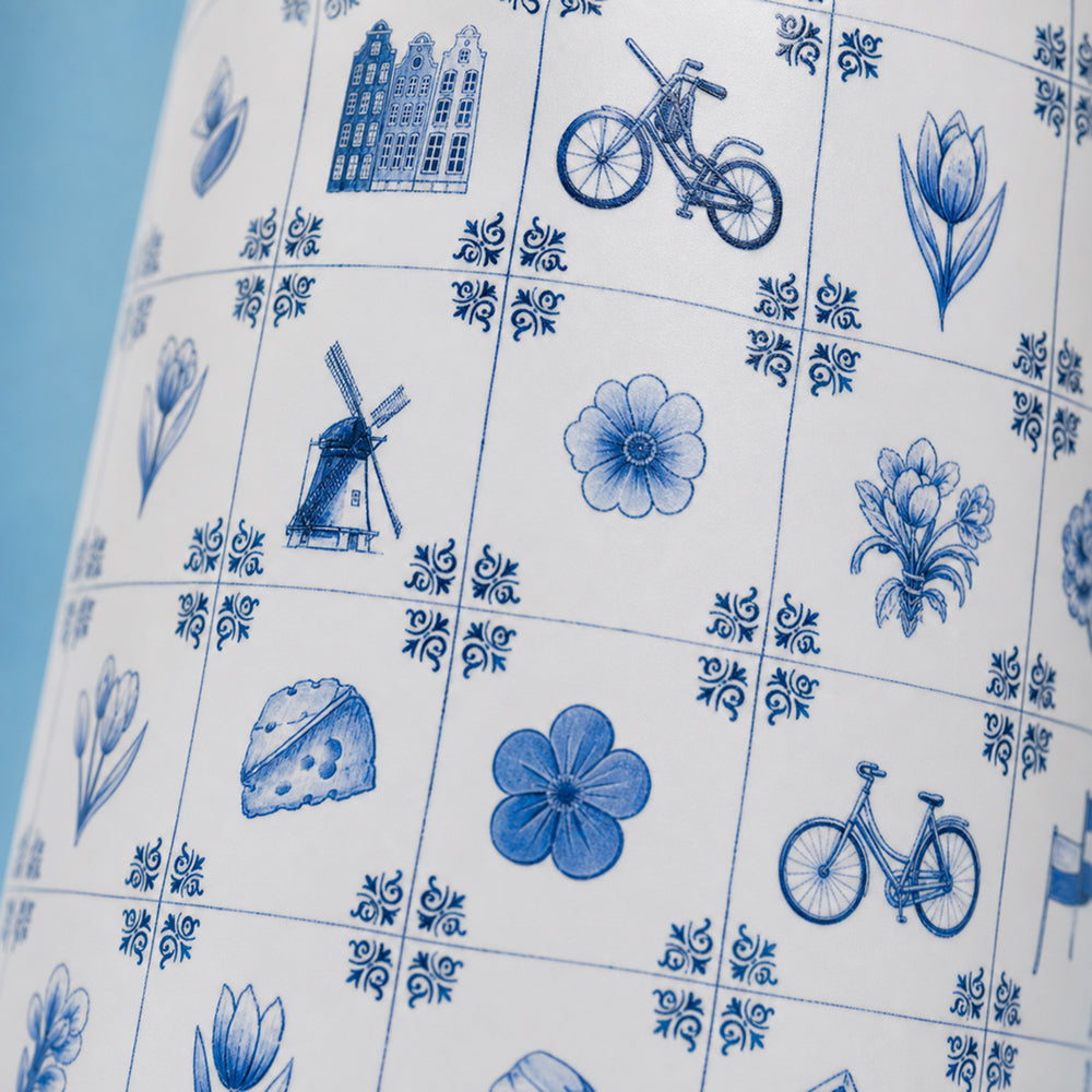 Close-up van het wit-blauwe tegelmotief met molen, fiets en tulp op de IZY Travel Bottle