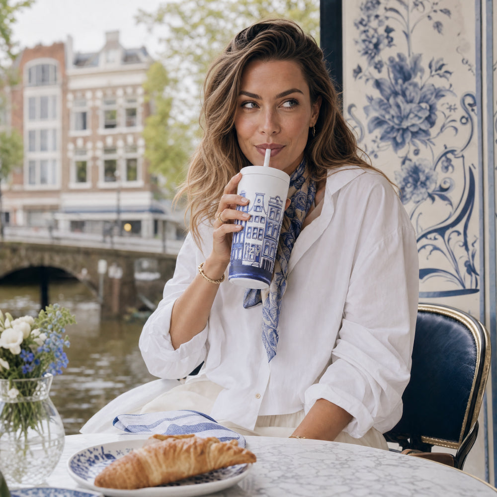 Vrouw drinkt met rietje uit de IZY Tumbler Canal House aan een terrastafel