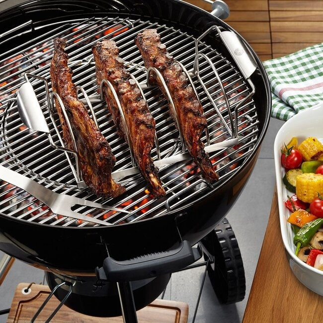 GEFU Spare Rib Rek met drie ribracks erin op een ronde kogelbarbecue boven gloeiende kolen