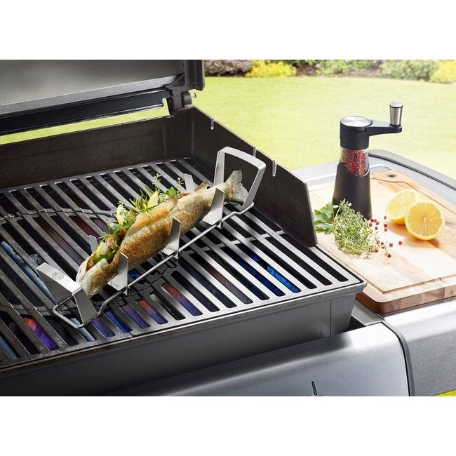 GEFU Visrek op de barbecue met een hele vis erin gevuld met kruiden, naast een pepermolen en citroen op een snijplank