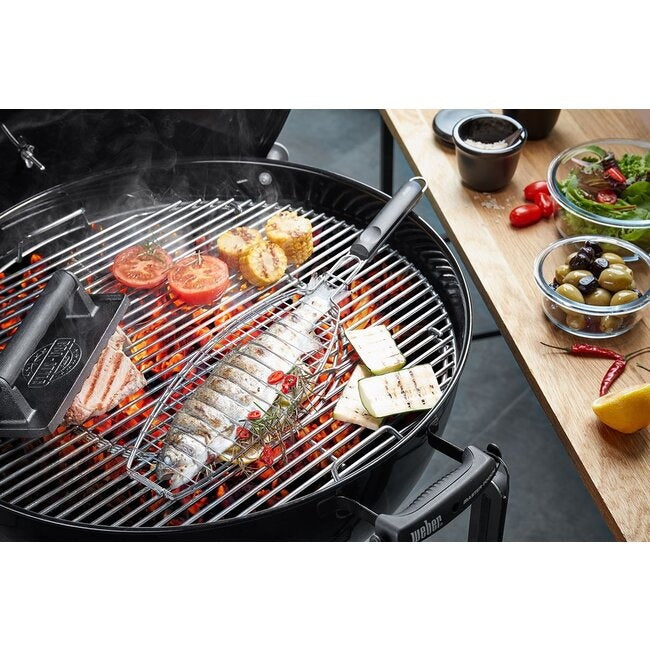 GEFU Vismand voor de Barbecue op de grill met een hele vis erin tussen gegrilde tomaten en brood, naast bakjes olijven en salade