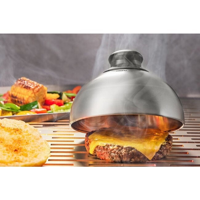 GEFU Hamburger- en Kaassmeltdeksel over een hamburger met gesmolten kaas op de grill, met stoom die opstijgt en een broodje en salade ernaast