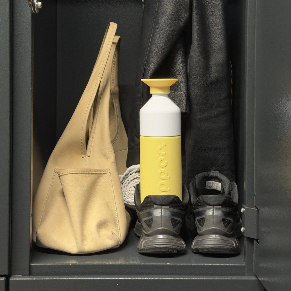 Dopper Insulated Maple Yellow tussen een tas en sneakers in een garderobekastje