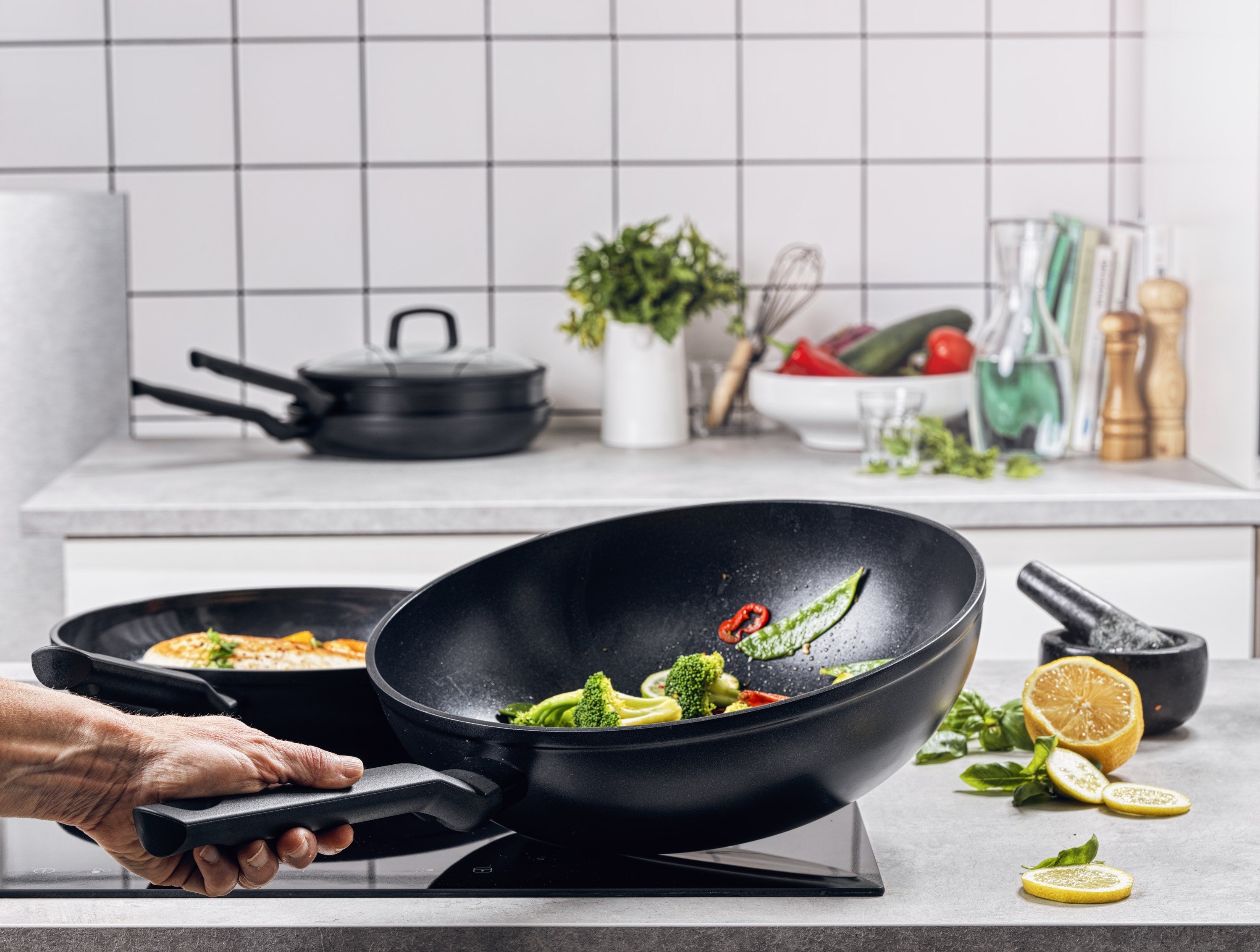 Zwarte BK Easy Induction wokpan met groenten op inductie, hand aan de steel.
