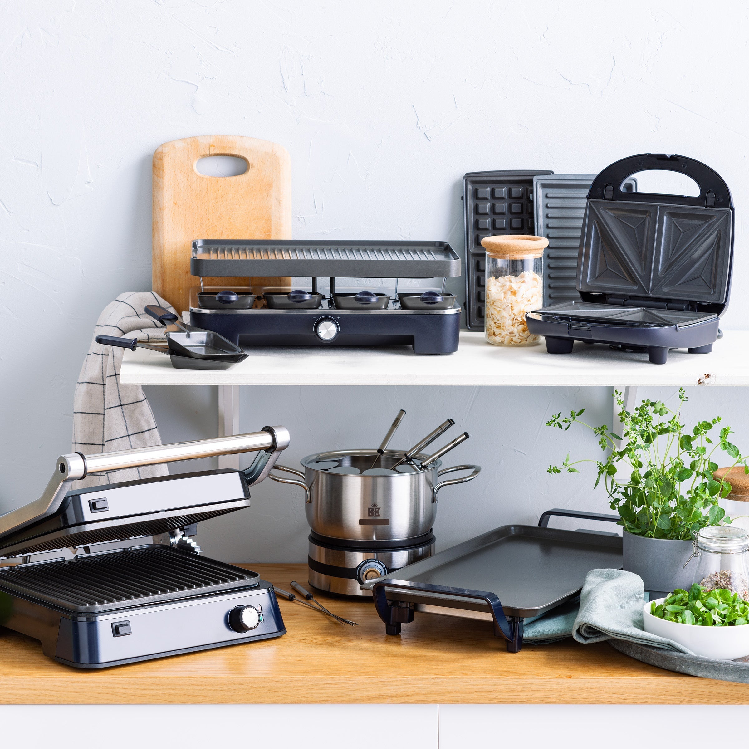 Collectie zwarte BK Connect apparaten op planken, waaronder raclette, grill en fondueset.