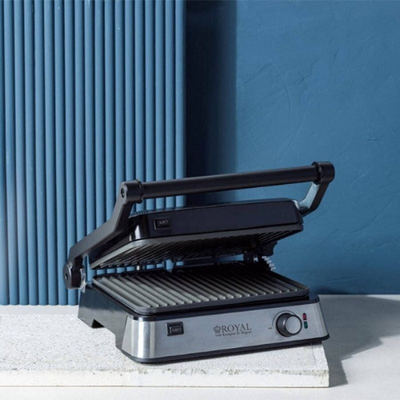 Royal Van Kempen contactgrill 180 graden platgeklapt en liggend op een lichte stenen sokkel, met een blauwe geribbelde wand op de achtergrond.