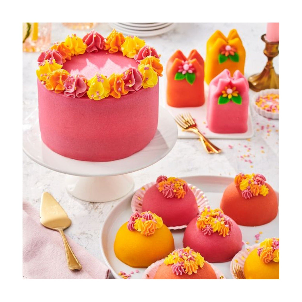 Roze taart met oranje en gele botercrème rozetten naast marsepein bonbons en bolvormige gebakjes