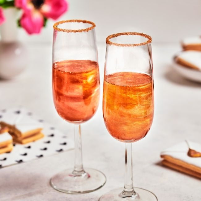Twee glazen bubbels met gouden glitter en suikerrand op de glazen