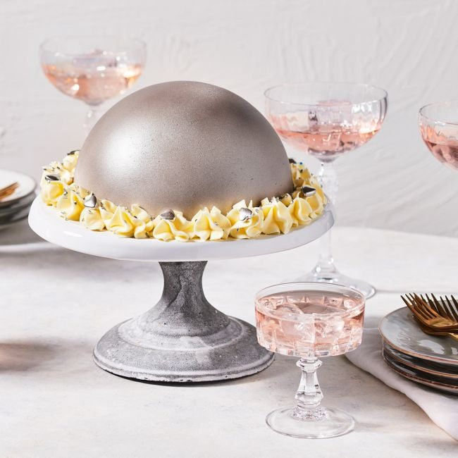 Bolvormige taart met zilveren glazuur en botercrème rozetten met zilveren decoraties op een taartstandaard
