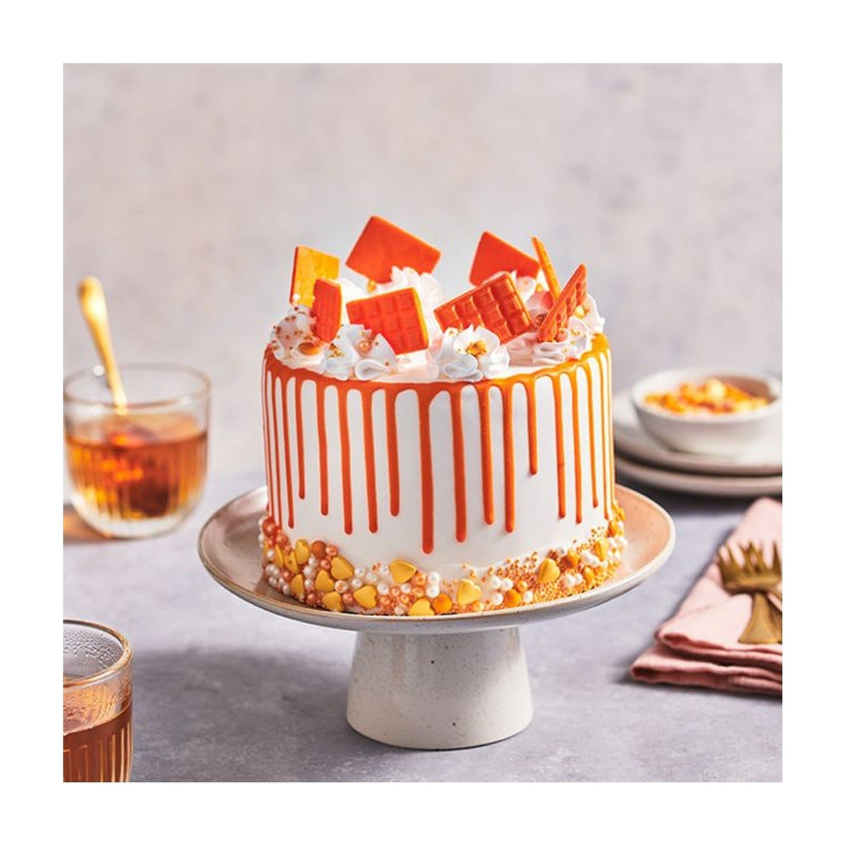 Taart met oranje drip en chocoladedecoraties op een taartplateau
