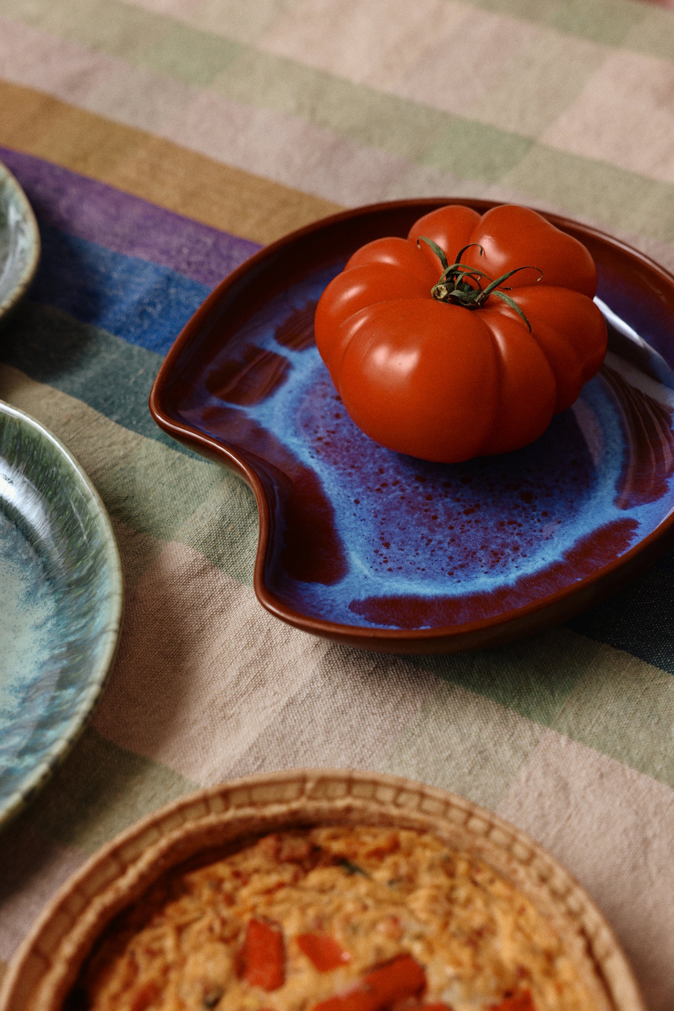 HKLiving Shell Bord Sienna met een tomaat op een geruit tafelkleed