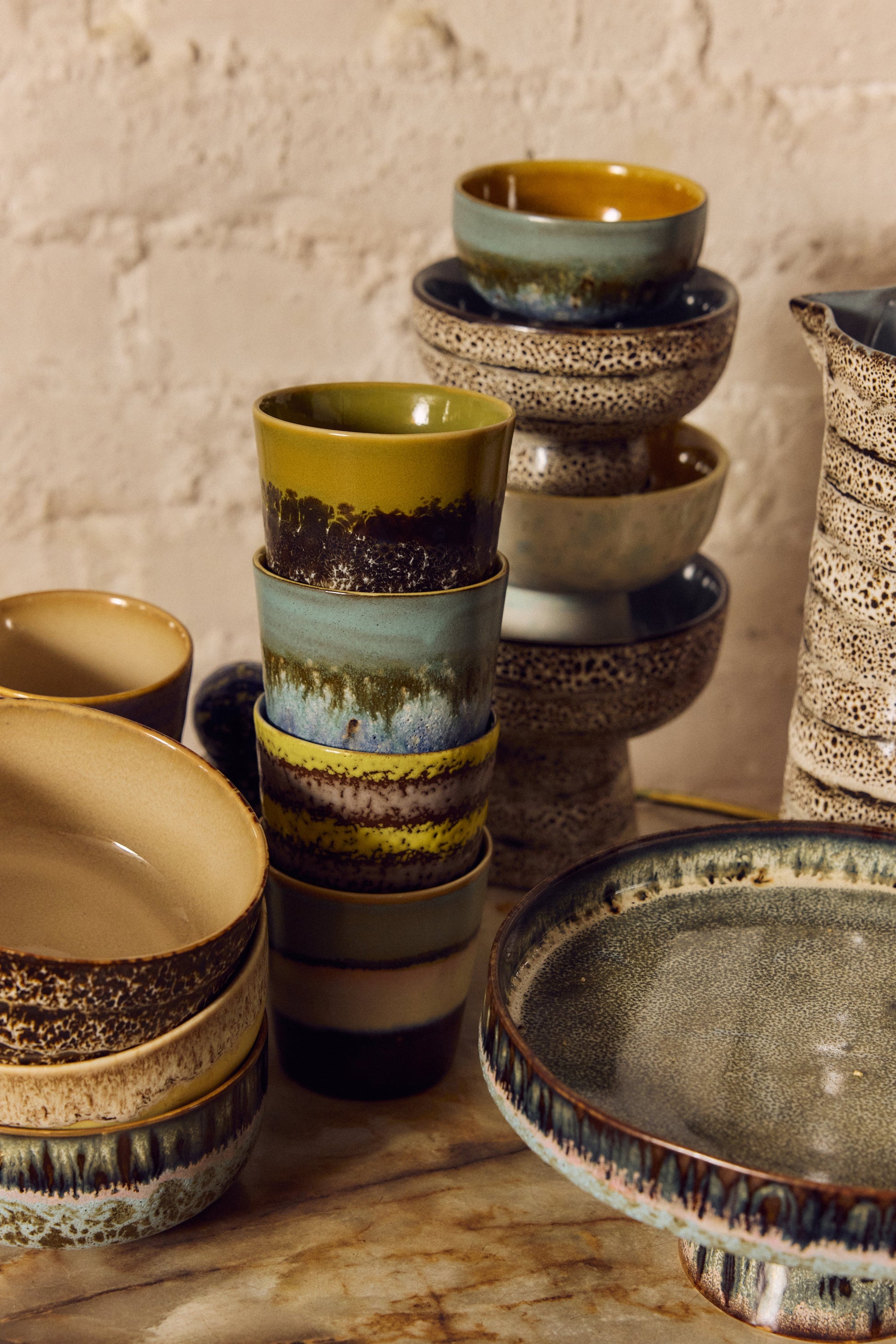 HKLiving 70's Koffiemok Truffle tussen andere kleuren uit de serie op een donkere tafel