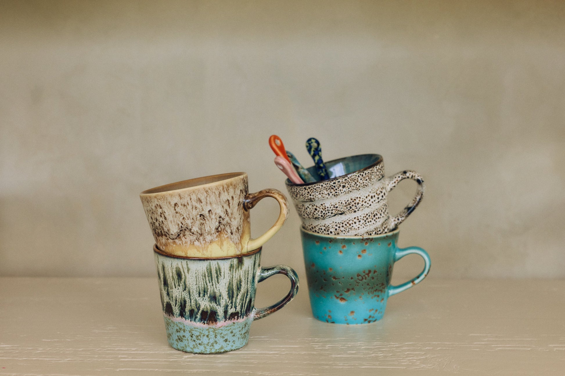 HKLiving 70's Americano Mok Custard, met een lepel erin naast een andere kleur uit de serie
