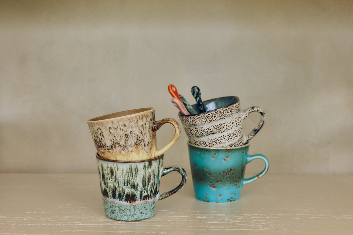 HKLiving 70's Americano Mok Aqua, met een lepel erin naast een andere kleur uit de serie