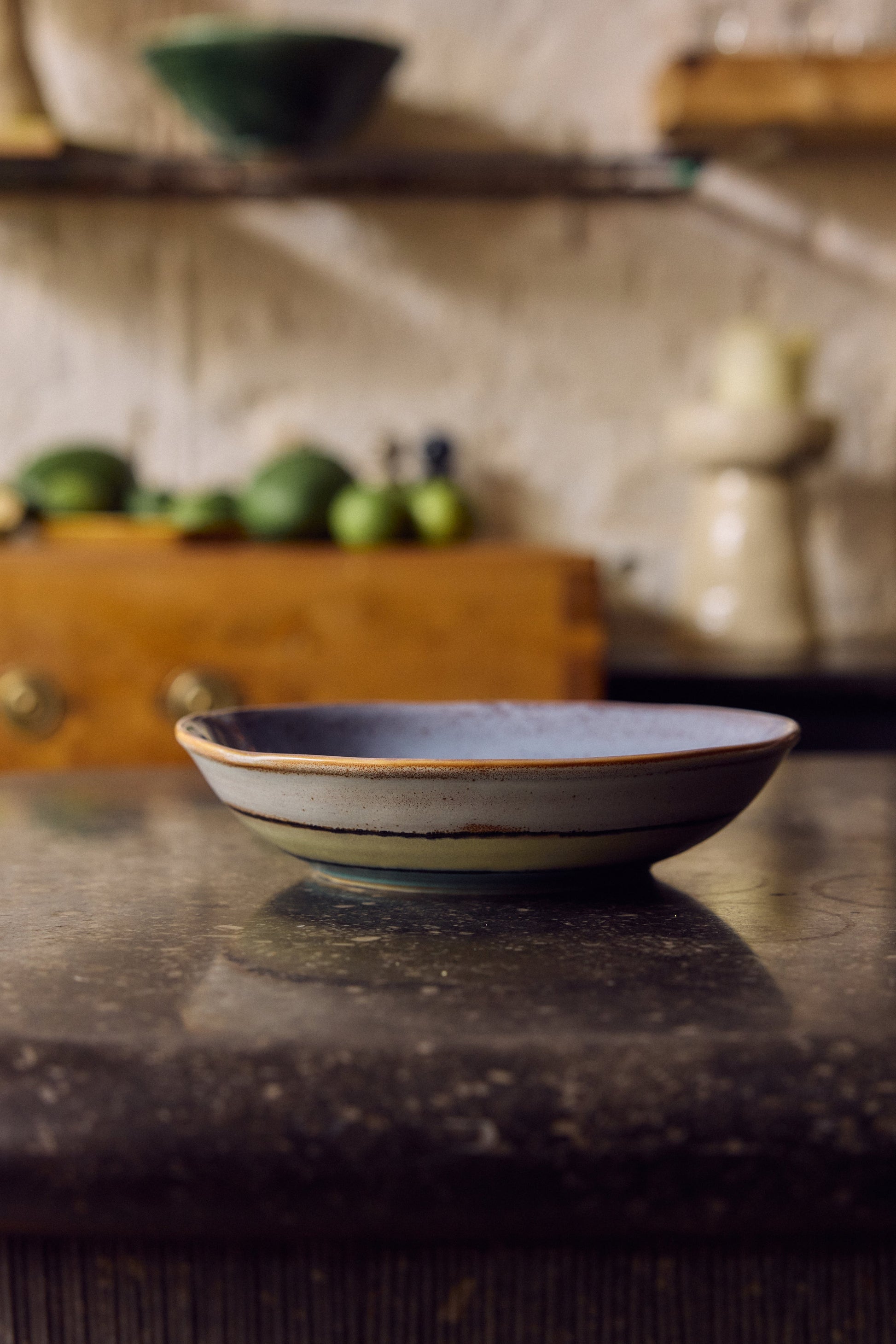 HKLiving 70's Curry Bowl Muted op een houten kastje tussen groene appels