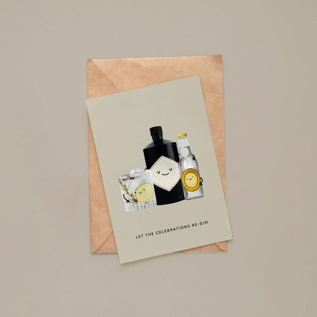 Wenskaart met gin-fles, tonic en gin-tonic glas, plat neergelegd op een kraftpapieren envelop tegen een taupe achtergrond