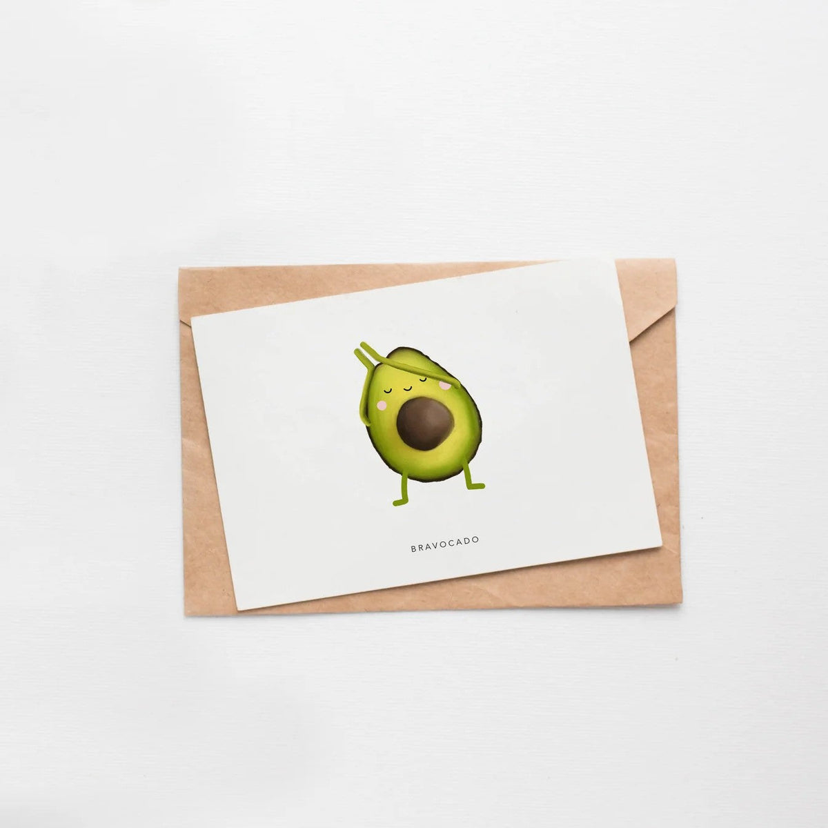 Wenskaart met een avocado-figuurtje met een schilletje als lintje, tekst Bravocado, op witte achtergrond