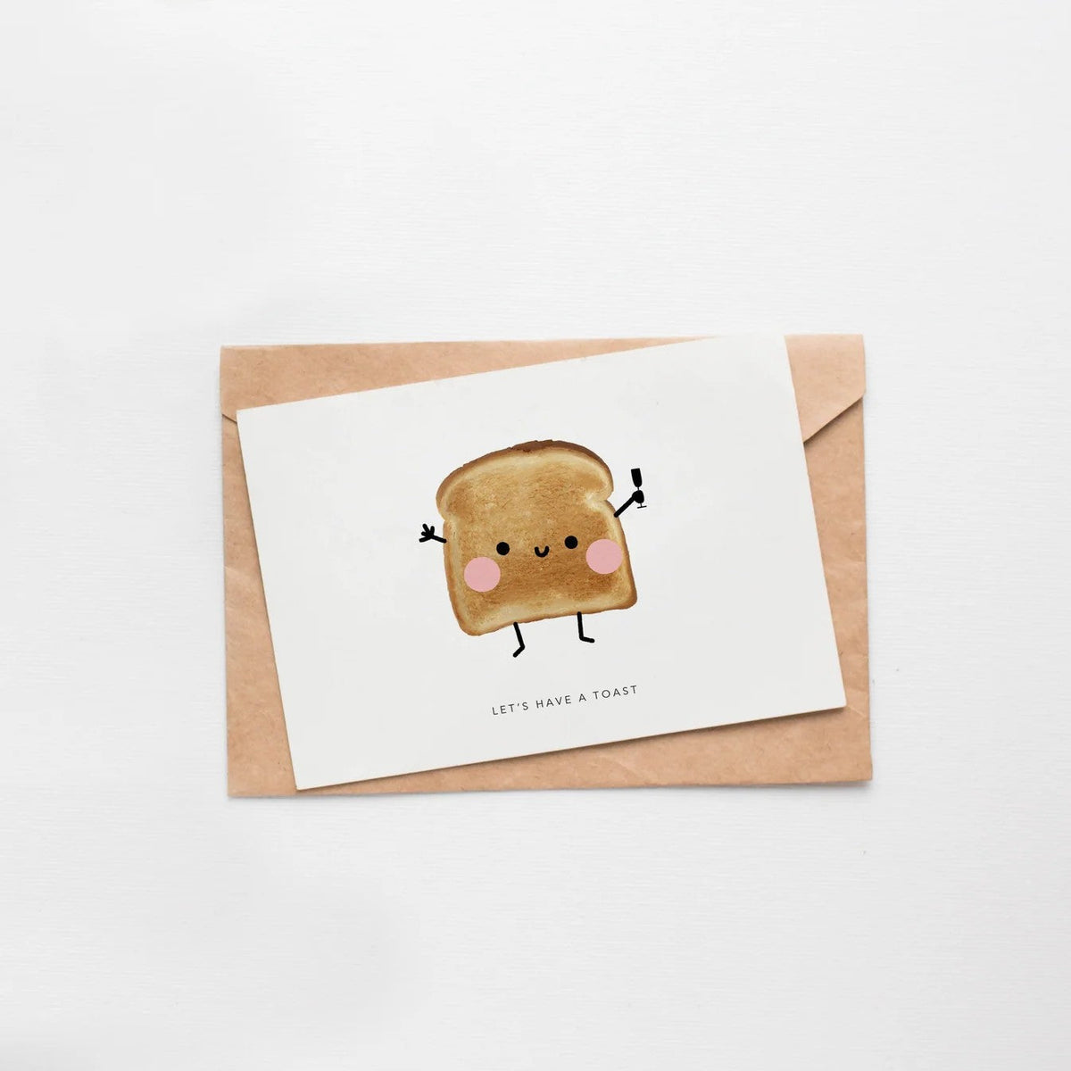 Wenskaart van Depre Design met een blozende boterham en champagneglaasje, op een kraft envelop tegen een witte achtergrond.