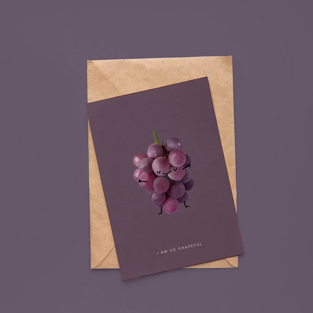 Paarse wenskaart met druiventros met gezichtje en tekst "I am so grapeful", op kraft envelop