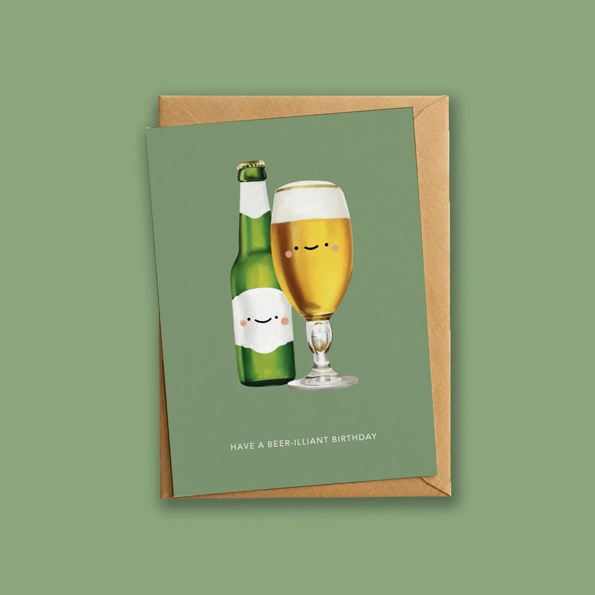 Wenskaart met bier-illustratie liggend op een kraft envelop tegen groene achtergrond