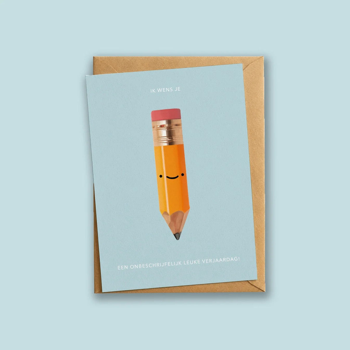 Wenskaart 'Een Onbeschrijfelijk Leuke Verjaardag' van Depre Design op lichtblauwe achtergrond, met een illustratie van een lachend potlood, kraftpapieren envelop eronder.