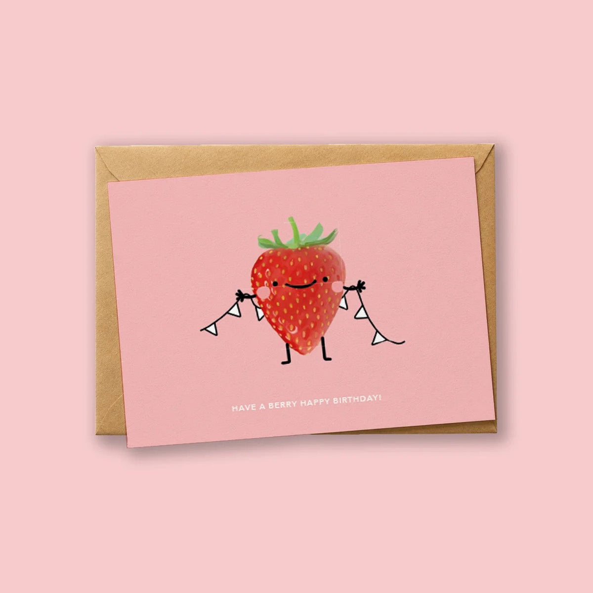 Wenskaart 'Have A Berry Happy Birthday' van Depre Design op roze achtergrond, met een illustratie van een blozende aardbei die twee vlaggenlijnen vasthoudt, kraftpapieren envelop eronder.