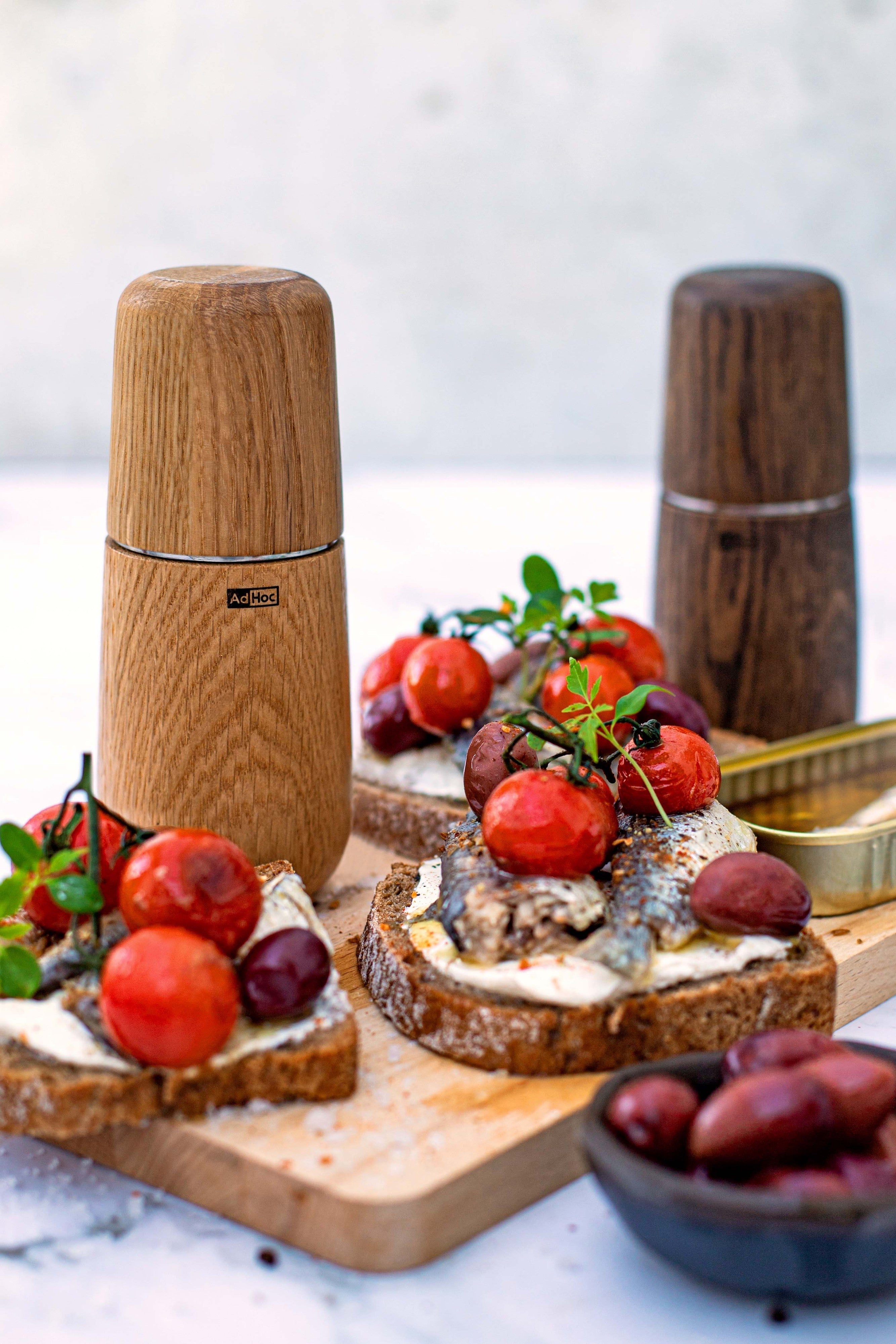 AdHoc Yono eikenhouten molens op een snijplank bij bruschetta met tomaat en olijven