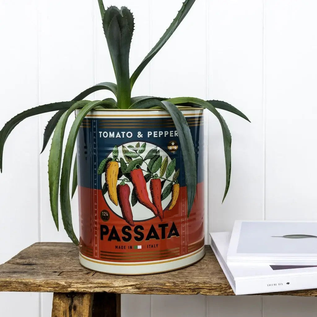 Groot Passata-blik met rode pepers op een blauw en rood etiket, met een agave erin, op een houten krukje naast een wit boek