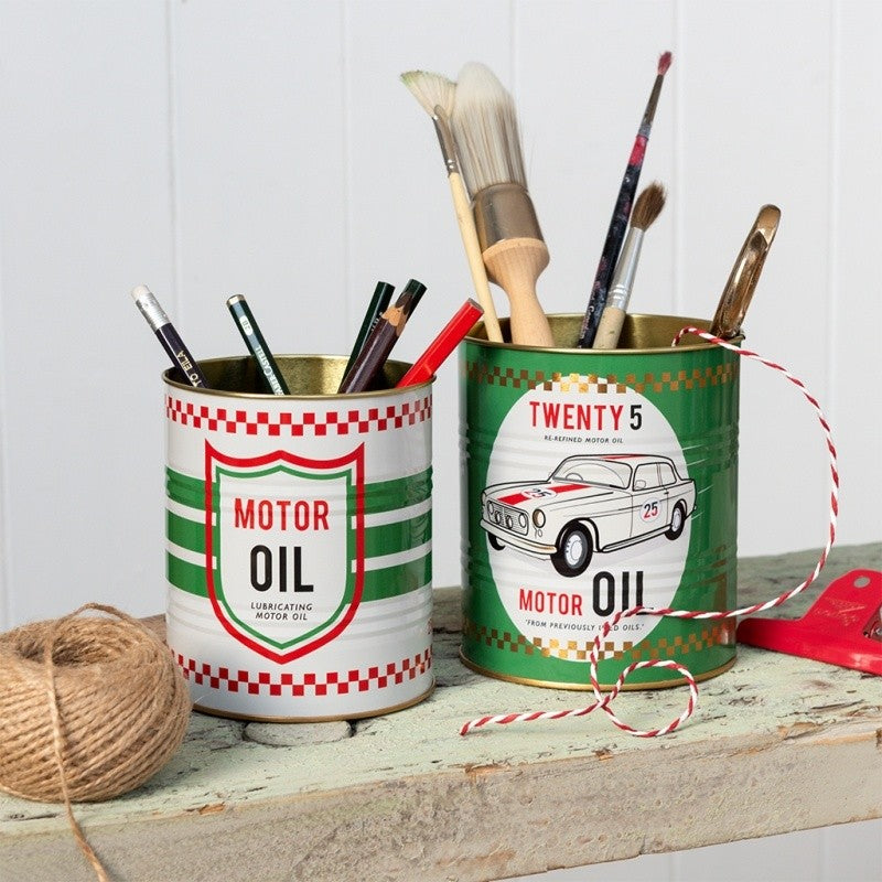 Twee retro blikken met Motor Oil-print op een lichtgroene houten bank, gevuld met potloden en kwasten, naast een bol touw en een rood-wit touwtje