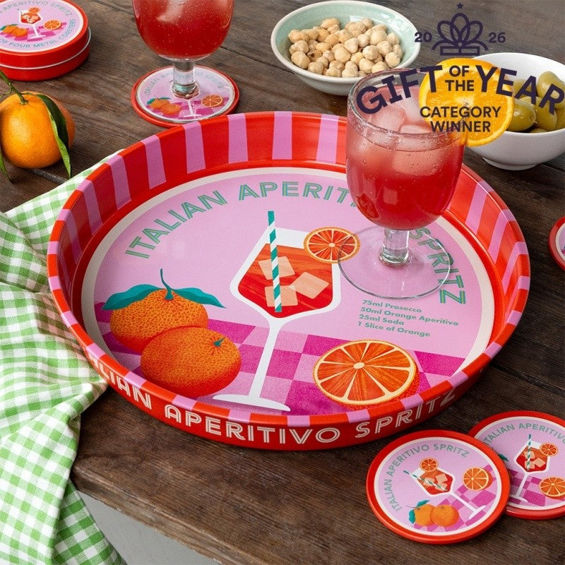 Het ronde gestreepte dienblad op een houten tafel met een glas spritz, een schaaltje noten, olijven, mandarijnen, een groen geruite doek en een blik met onderzetters