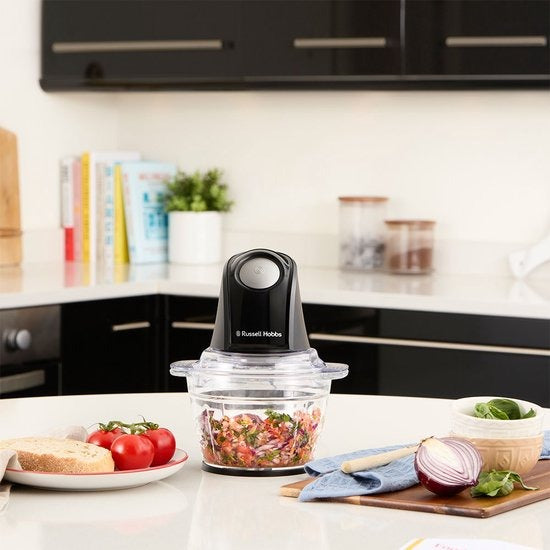 Russell Hobbs Mini Chopper, gevuld met gehakte groenten op een keukenblad naast tomaten en brood