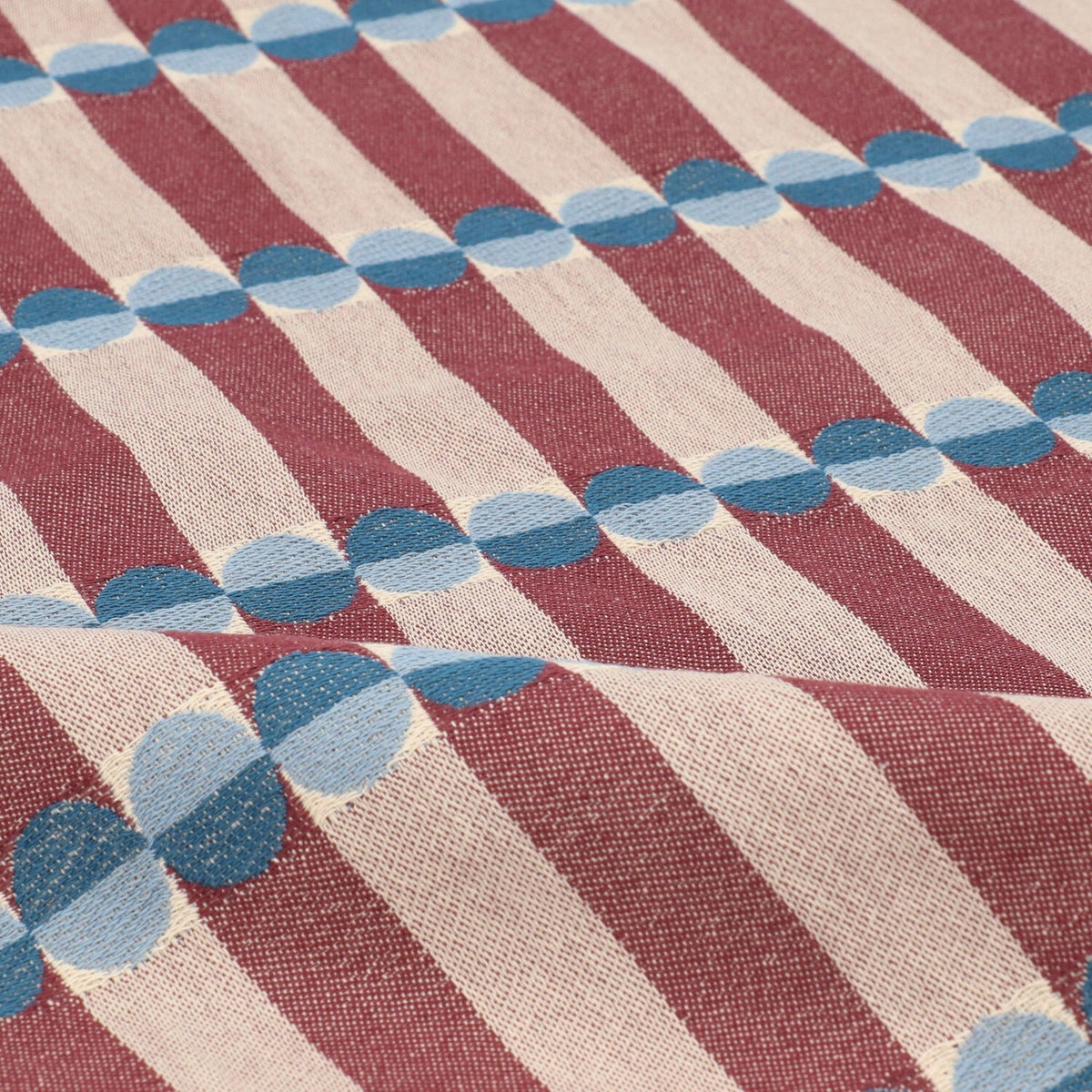 Theedoek Natural Ana - Burgundy, close-up van blauwe halve cirkels op bordeauxrode en taupe strepen met een plooi