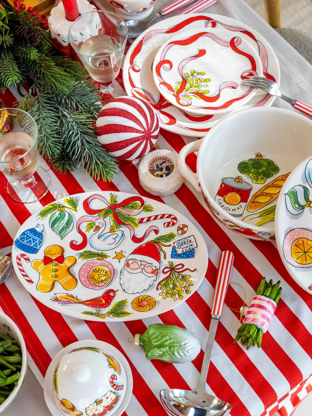 Het ovale bord op een kersttafel met een rood en wit gestreepte loper en dennentakken