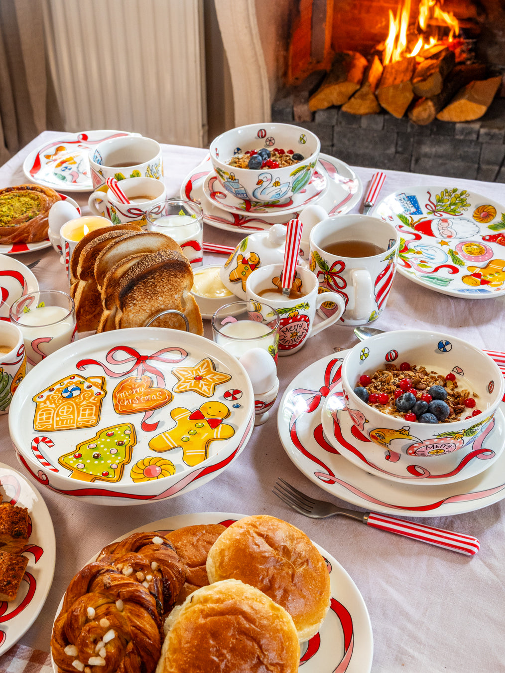 Ontbijttafel bij een open haard met servies uit de Kerst-collectie en kleine mokken