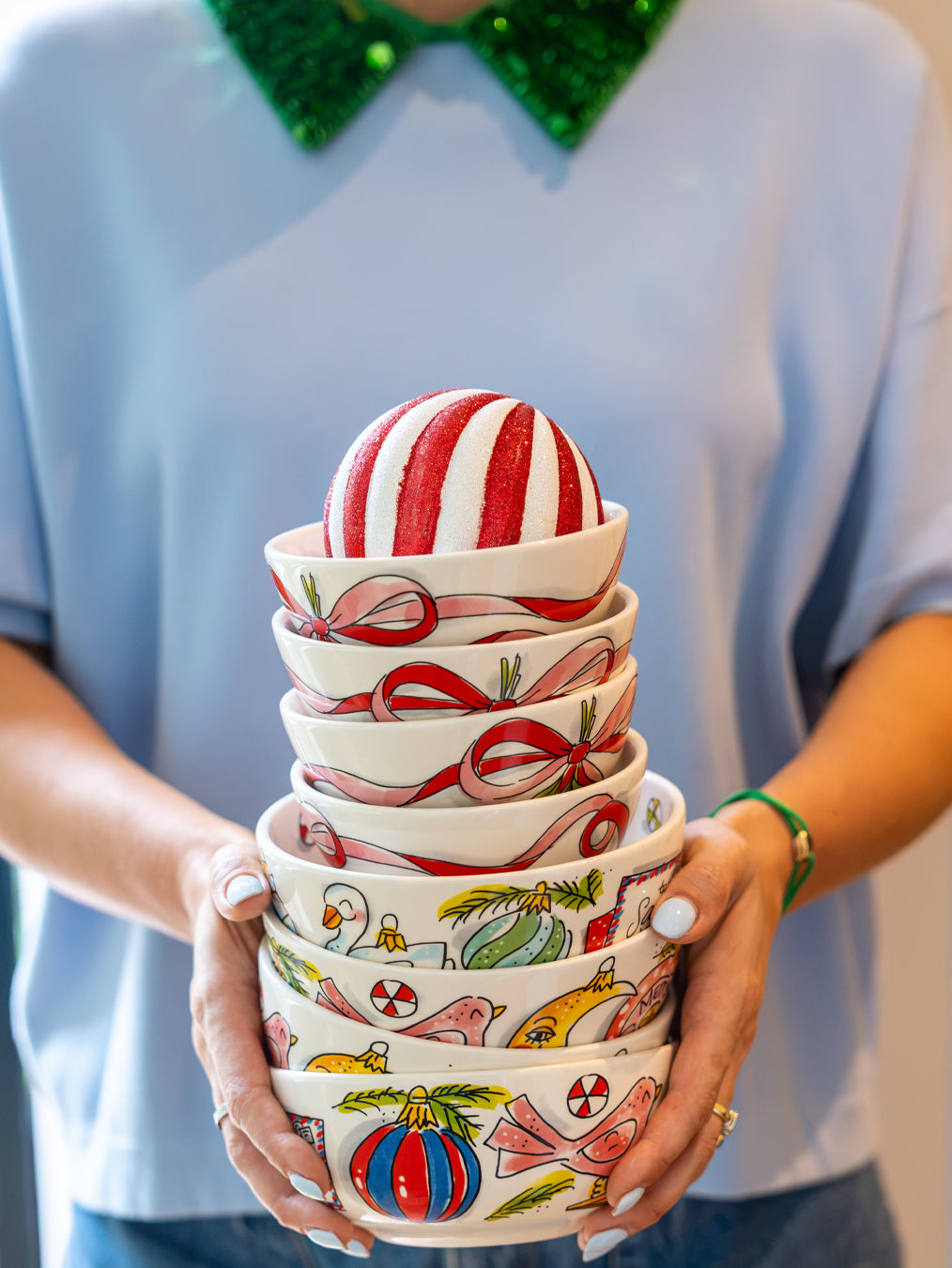 Een vrouw houdt een stapel kommen met linten en kerstballen vast